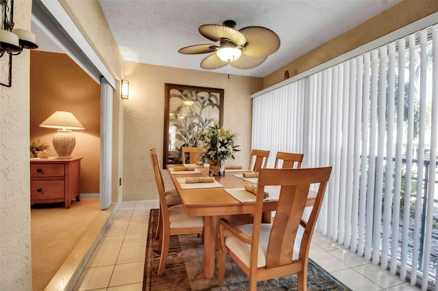 dining area featuring light tile patterned flooring, a textured wall, and ceiling fan