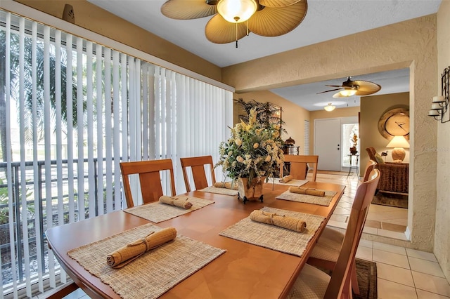 dining space with a textured wall, a ceiling fan, and tile patterned floors