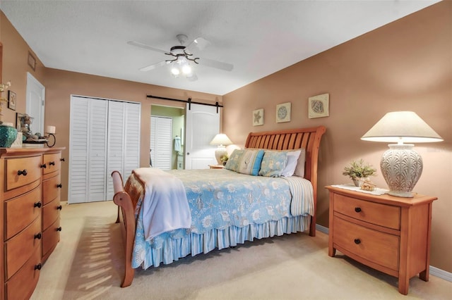 bedroom with a ceiling fan, light carpet, baseboards, and a barn door