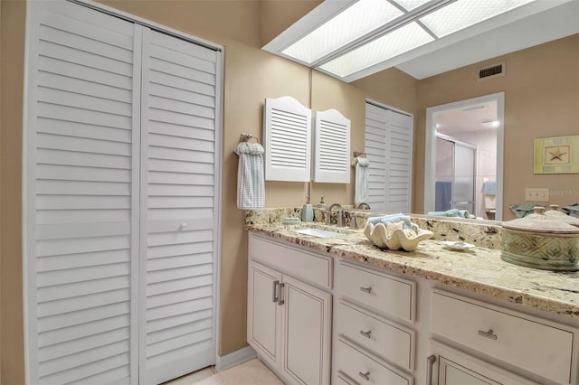 full bathroom featuring a skylight, a shower stall, visible vents, and vanity