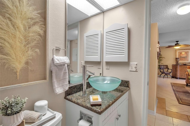 bathroom featuring a skylight, ceiling fan, a textured ceiling, vanity, and tile patterned floors