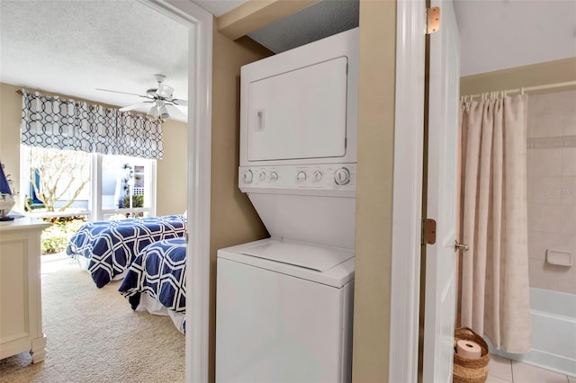 laundry area with stacked washer / dryer, carpet flooring, ceiling fan, a textured ceiling, and laundry area