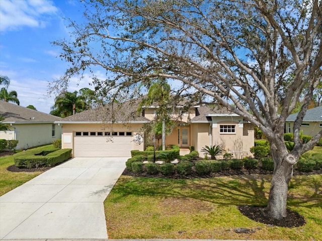 view of front facade with a garage, a front yard, concrete driveway, and stucco siding