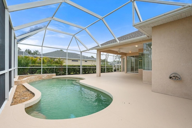 outdoor pool with glass enclosure, a ceiling fan, and a patio