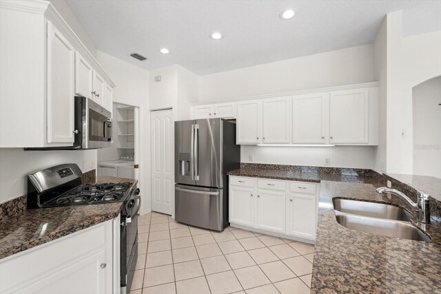 kitchen with appliances with stainless steel finishes, washer and clothes dryer, a sink, and white cabinets