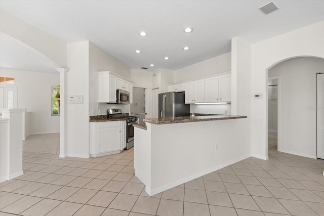 kitchen with a peninsula, light tile patterned floors, white cabinetry, and stainless steel appliances