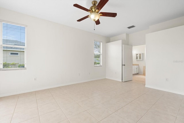 empty room with light tile patterned floors, baseboards, visible vents, and ceiling fan