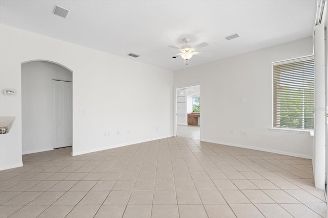 unfurnished room featuring visible vents, arched walkways, baseboards, ceiling fan, and light tile patterned flooring