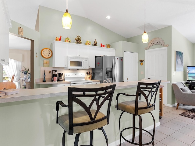 kitchen with a breakfast bar area, light tile patterned flooring, white appliances, light countertops, and decorative light fixtures