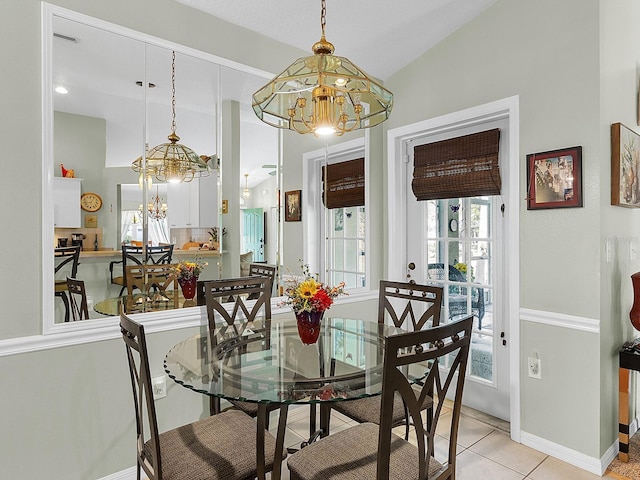 dining space featuring vaulted ceiling, light tile patterned flooring, baseboards, and a notable chandelier