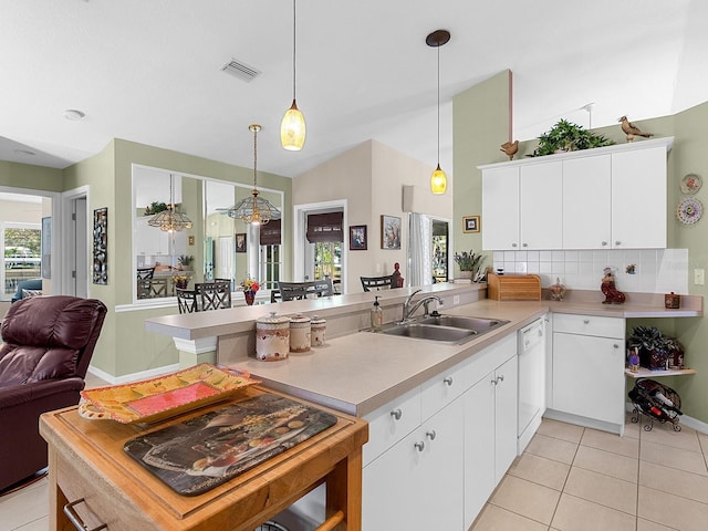 kitchen featuring light tile patterned floors, dishwasher, a peninsula, light countertops, and a sink