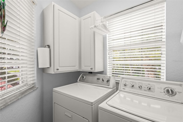 laundry area with cabinet space, separate washer and dryer, and a textured wall