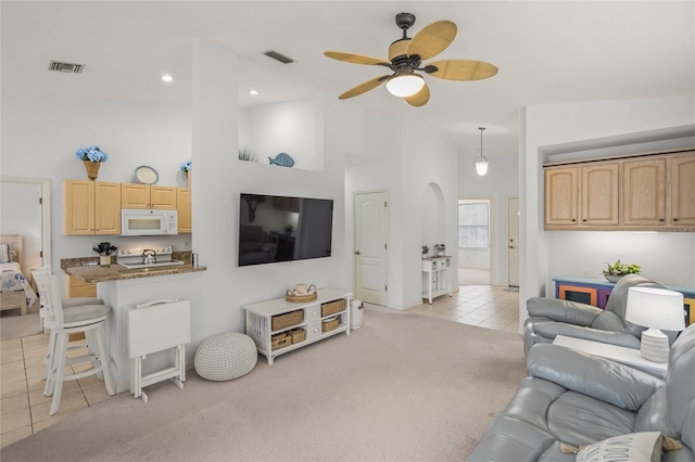 living area with light tile patterned flooring, light colored carpet, visible vents, and high vaulted ceiling