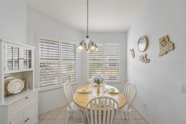 dining space with an inviting chandelier, light tile patterned floors, and baseboards