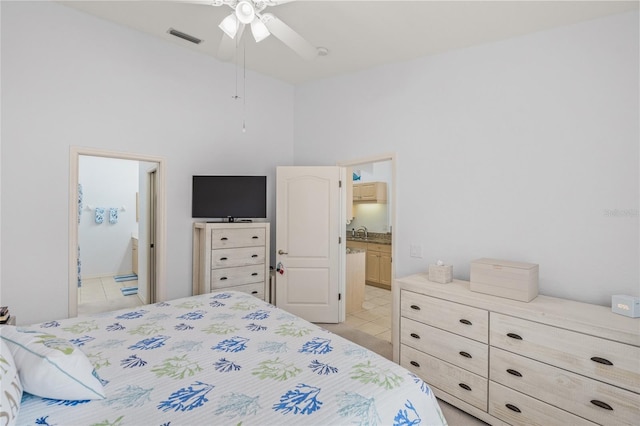 bedroom with visible vents, ensuite bathroom, a sink, light tile patterned floors, and a towering ceiling