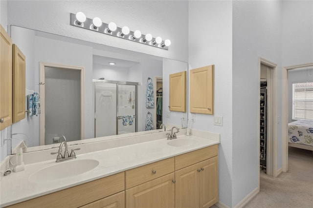 full bathroom featuring a sink, baseboards, a stall shower, and double vanity