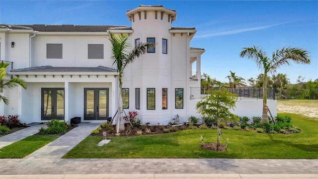 view of front of house with french doors, stucco siding, a front lawn, and a tile roof