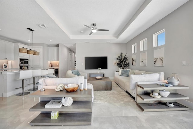 6027 White Mangrove Ln, Bradenton, FL 34210 - living room featuring visible vents, ceiling fan, baseboards, a tray ceiling, and a textured ceiling