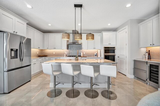 6027 White Mangrove Ln, Bradenton, FL 34210 - kitchen with a kitchen island with sink, stainless steel appliances, beverage cooler, and white cabinetry