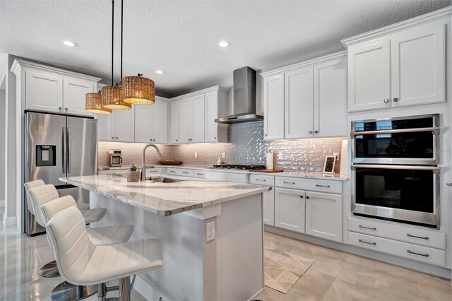 6027 White Mangrove Ln, Bradenton, FL 34210 - kitchen with tasteful backsplash, light stone countertops, appliances with stainless steel finishes, wall chimney exhaust hood, and a sink
