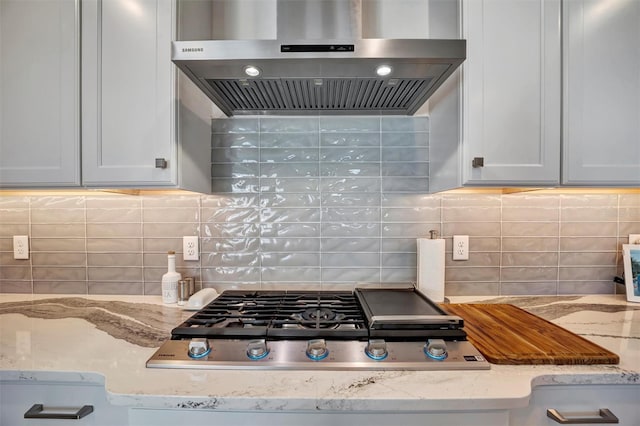 6027 White Mangrove Ln, Bradenton, FL 34210 - kitchen with decorative backsplash, wall chimney range hood, light stone counters, and stainless steel gas stovetop