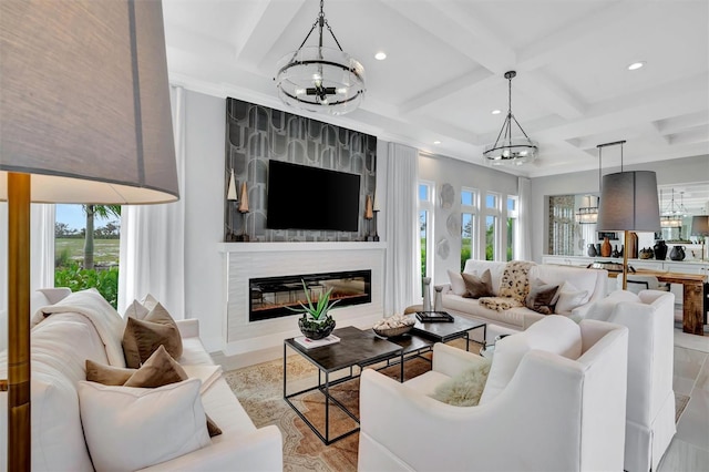 living area with a glass covered fireplace, recessed lighting, coffered ceiling, and a chandelier