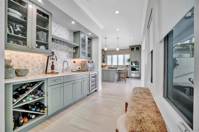 interior space featuring gray cabinetry, wine cooler, ornamental molding, decorative backsplash, and a sink