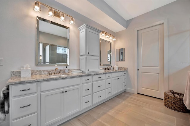 bathroom featuring double vanity, a shower stall, and a sink