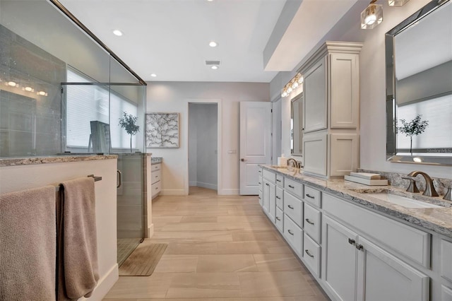 bathroom featuring a sink, a shower stall, recessed lighting, and double vanity