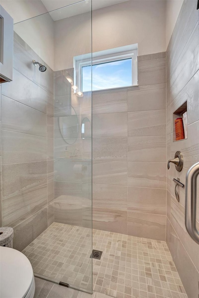 full bath with toilet and a tile shower