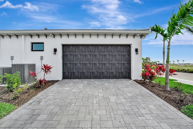 garage with central air condition unit and decorative driveway