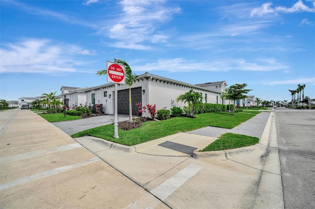 view of front of home with a garage, a residential view, a front yard, and driveway