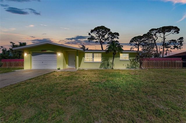 ranch-style house featuring stucco siding, a front yard, driveway, and fence