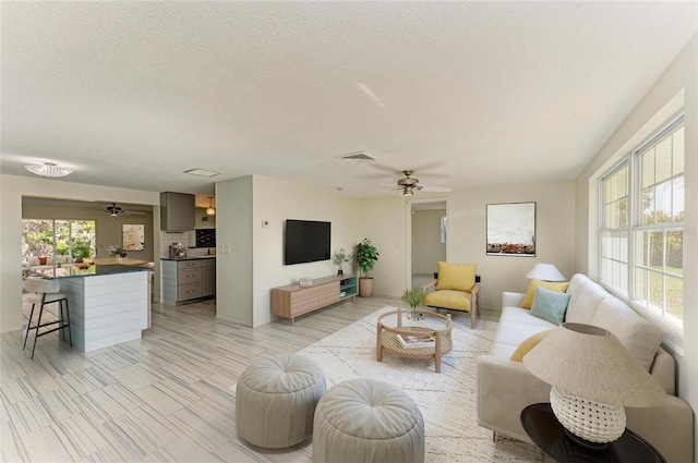 living room featuring a textured ceiling, visible vents, and ceiling fan