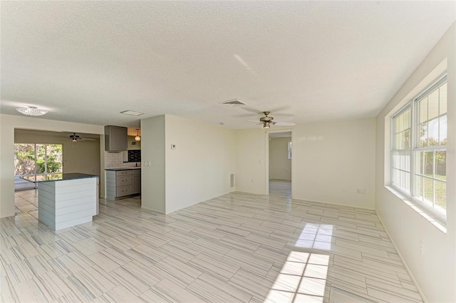 unfurnished room with visible vents, a textured ceiling, and a ceiling fan