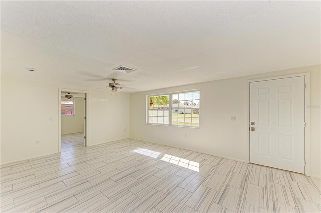 empty room featuring visible vents, a textured ceiling, and a ceiling fan