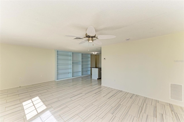 spare room with a ceiling fan, visible vents, and a textured ceiling