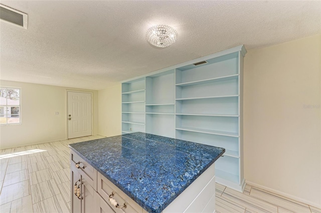 kitchen with open shelves, visible vents, a textured ceiling, and a center island