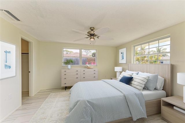 bedroom featuring visible vents, a textured ceiling, and ceiling fan