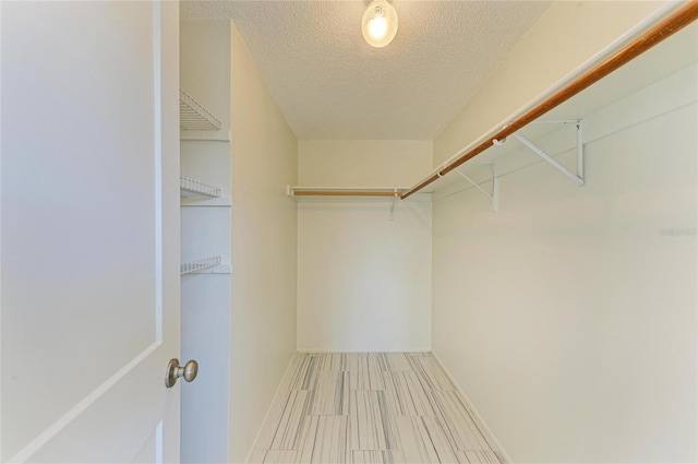 walk in closet with wood finish floors