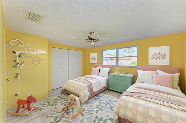 bedroom featuring visible vents, ceiling fan, light wood-style floors, a closet, and a textured ceiling