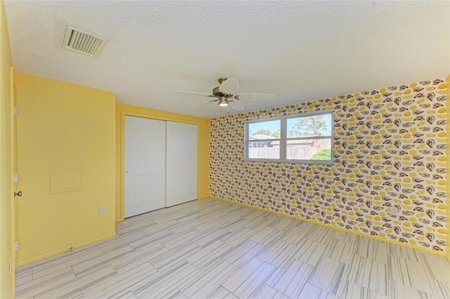 unfurnished bedroom featuring a closet, visible vents, a textured ceiling, and ceiling fan