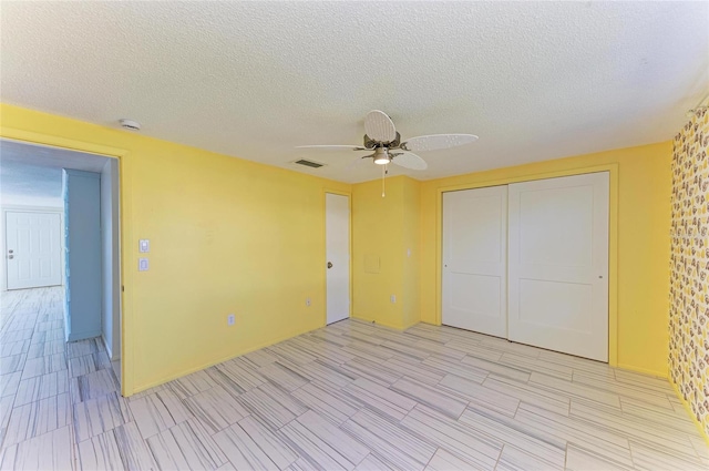 unfurnished bedroom with a textured ceiling, visible vents, a closet, and ceiling fan