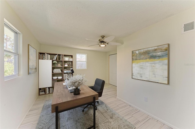 home office featuring visible vents, plenty of natural light, a textured ceiling, and a ceiling fan