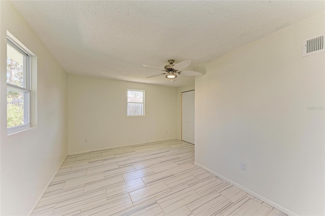 unfurnished room with baseboards, visible vents, a textured ceiling, and ceiling fan