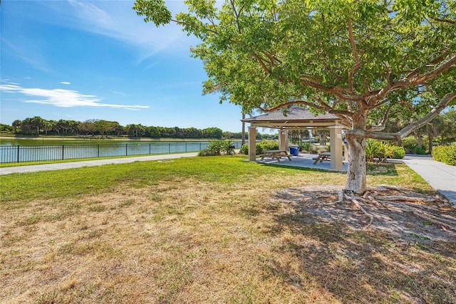 view of yard featuring a gazebo, a water view, and fence