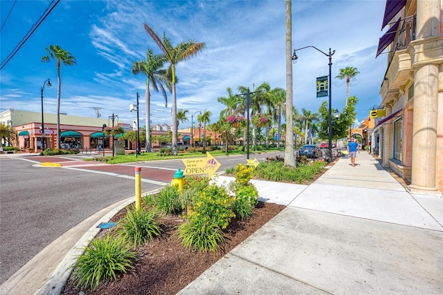 view of road featuring sidewalks, curbs, street lights, and traffic signs