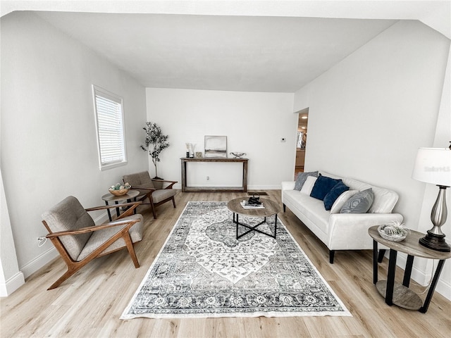 living room with lofted ceiling, light wood-style flooring, and baseboards