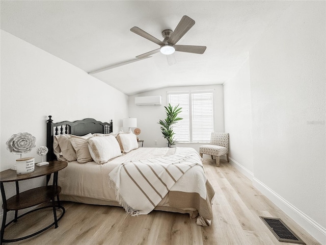 bedroom featuring visible vents, baseboards, vaulted ceiling, an AC wall unit, and light wood-style floors