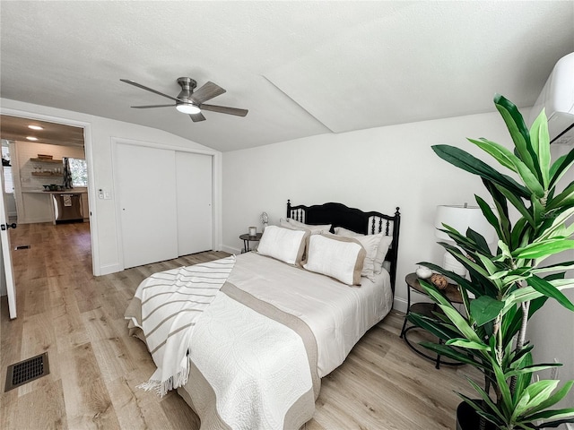 bedroom featuring visible vents, a ceiling fan, vaulted ceiling, a closet, and light wood finished floors